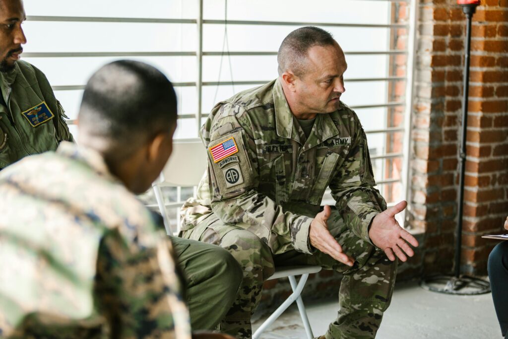 pexels-photo-7467911-7467911 Military veterans engaging in a supportive group therapy session indoors.